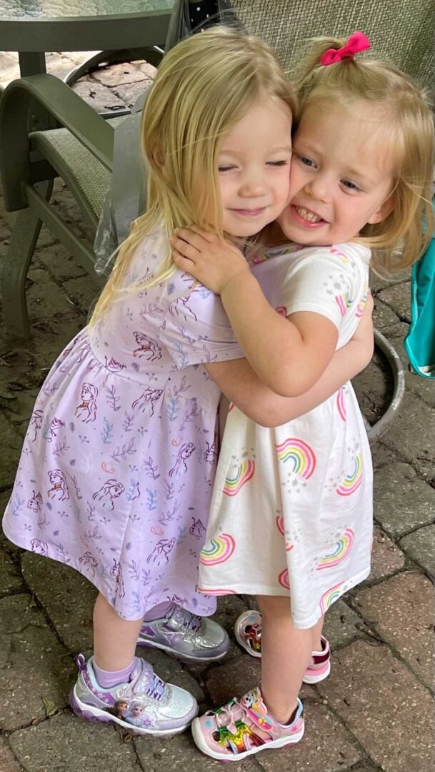 Two blonde little girls hugging each other