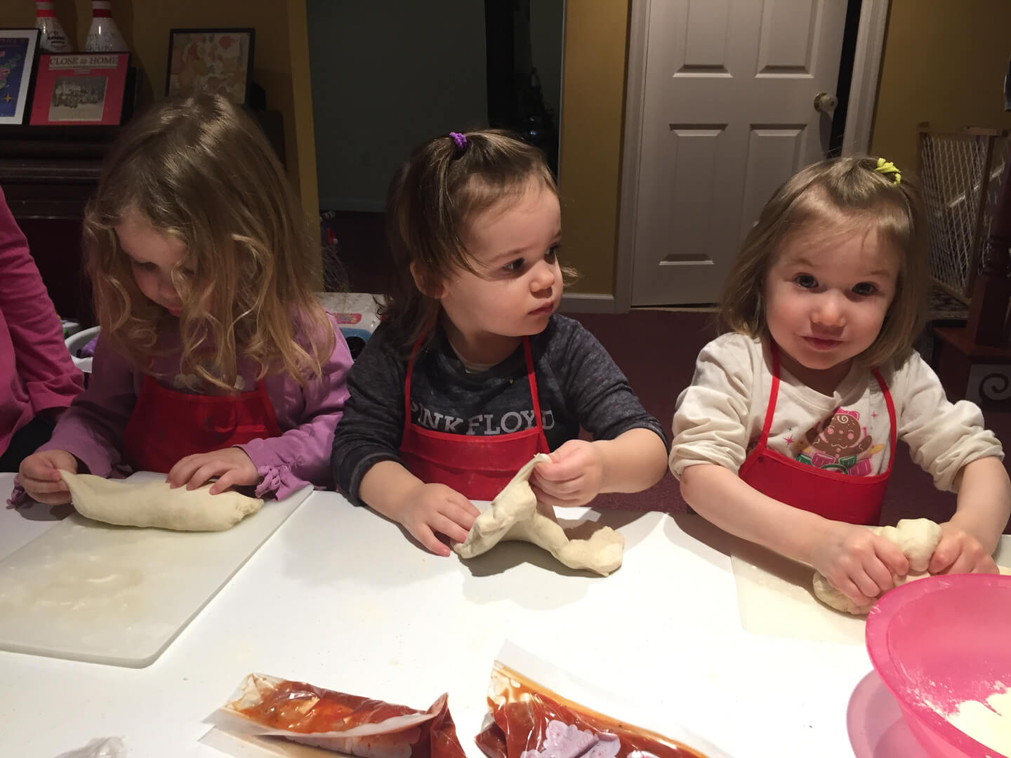 Three girls rolling dough