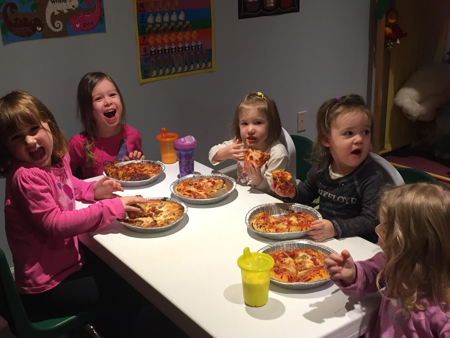 Five girls eating homemade pizza indoors