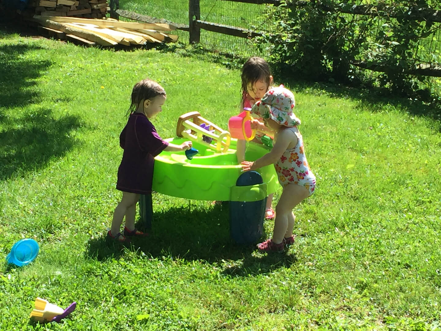 Three kids playing with toys in the yard