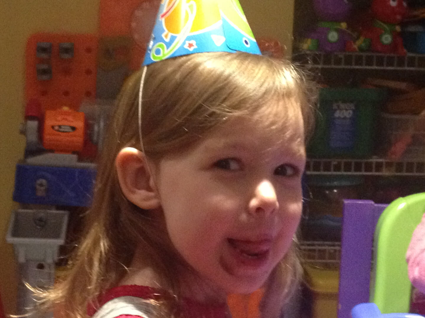 Young girl with a birthday hat licking her lips