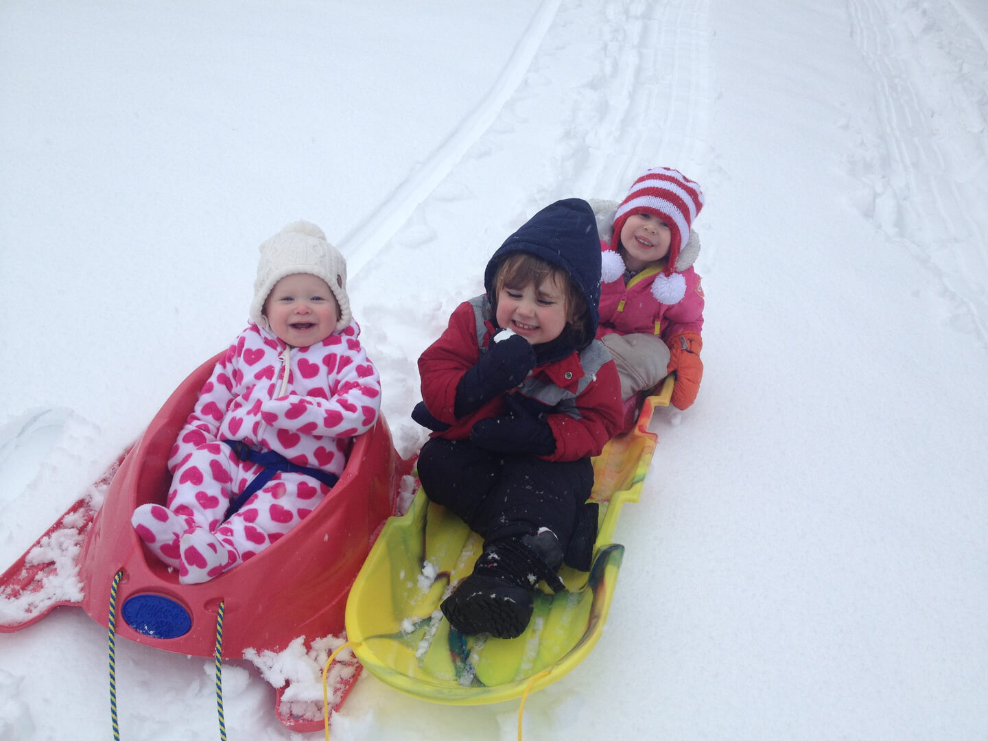 Three kids sleighing through snow