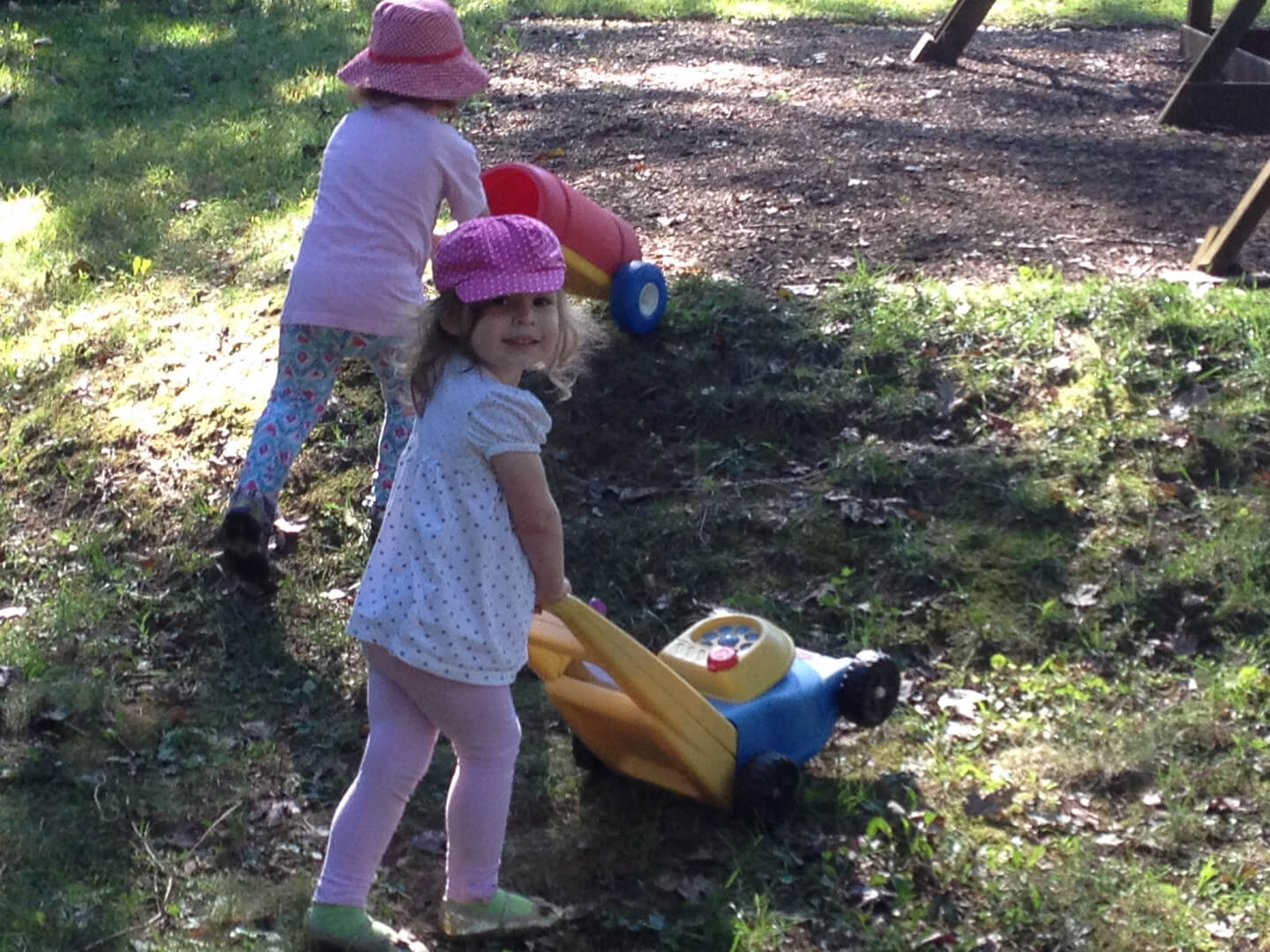 Two young girls playing with toy gardening equipment