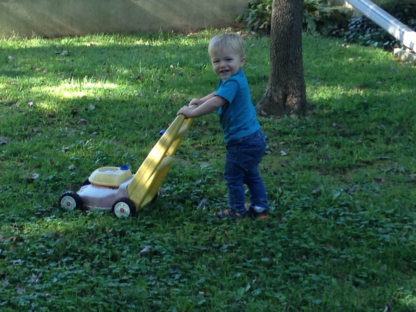 Kid playing with a toy lawnmower
