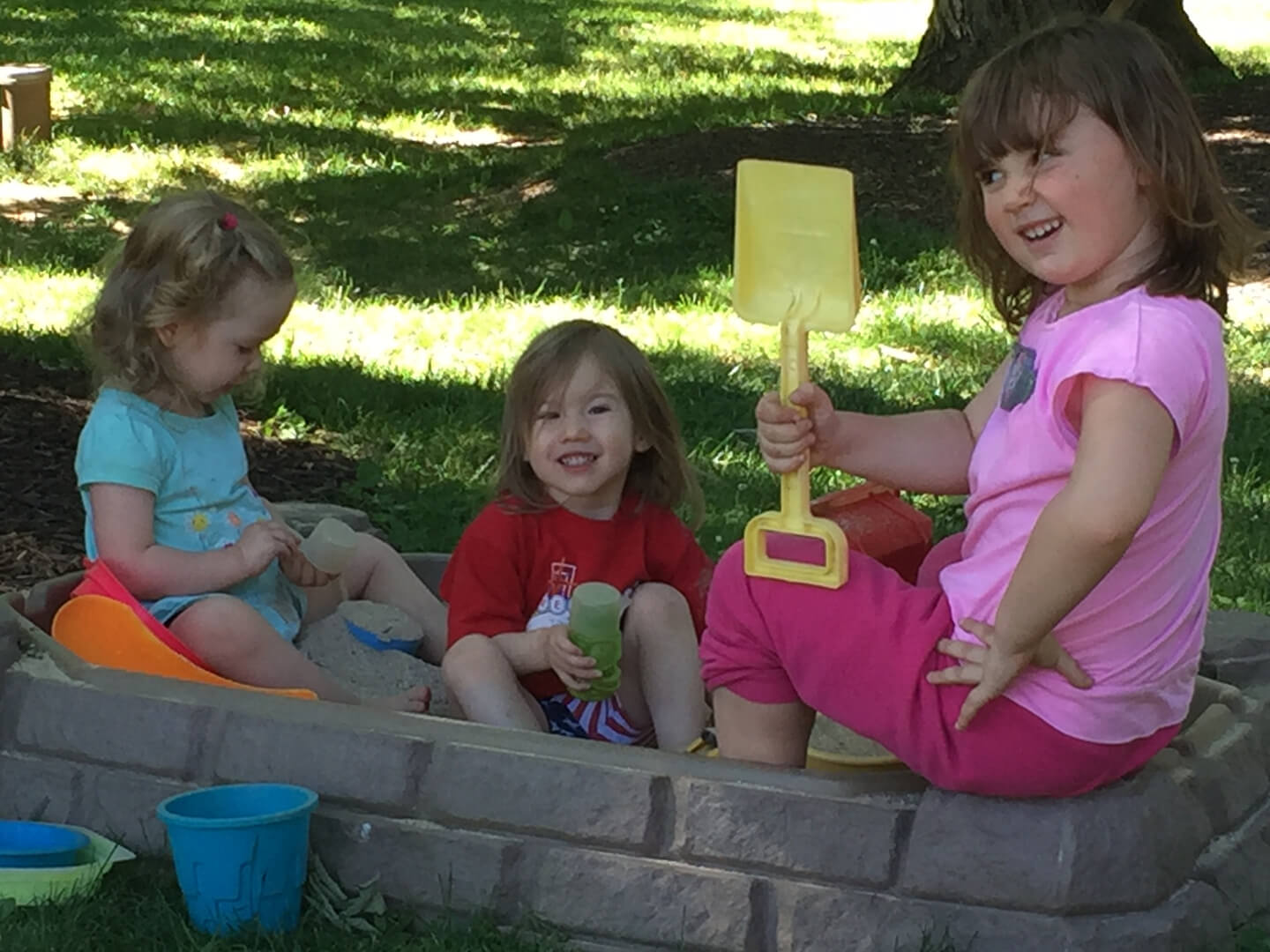 Three young girls playing in a sandbox
